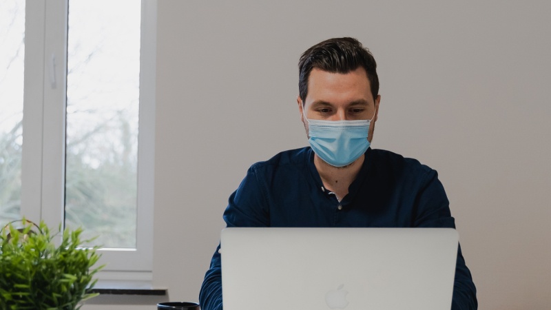 man with face mask on a laptop